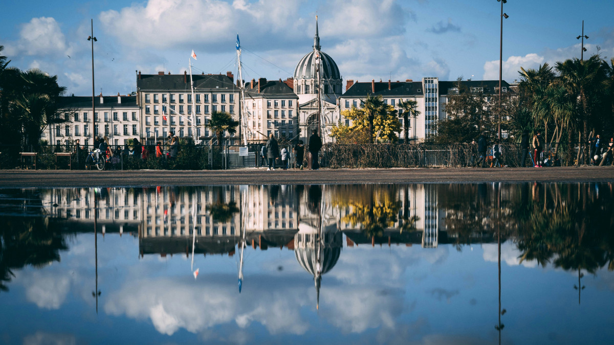 Le monument de Nantes se reflète sur l'eau sous un ciel bleu